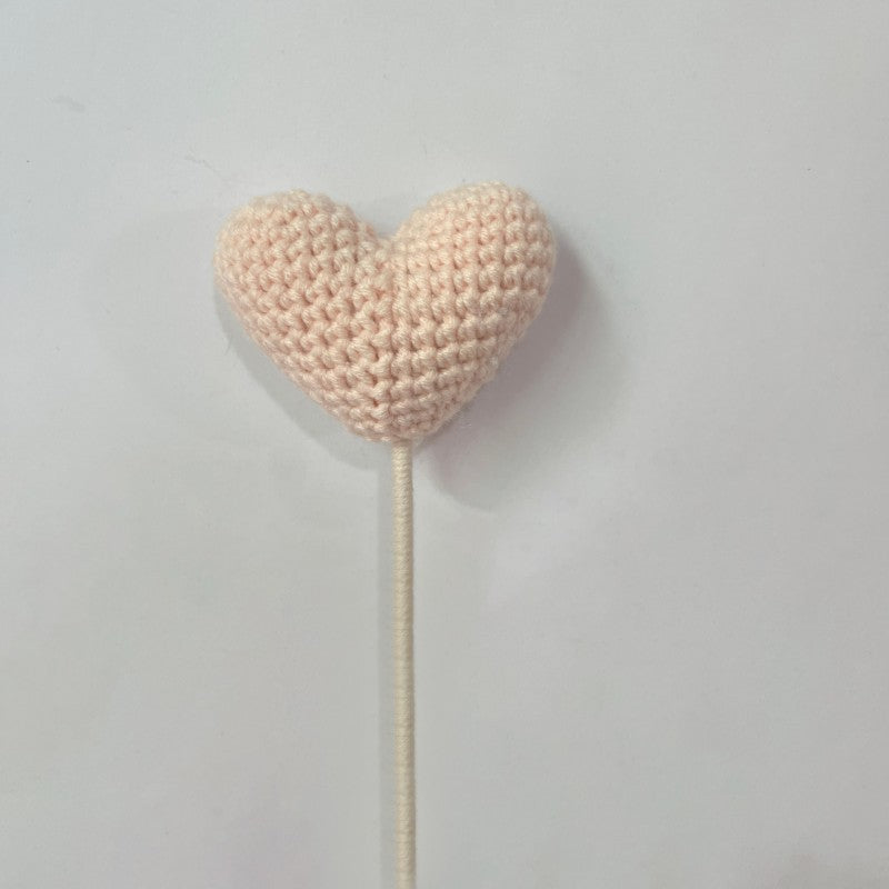 Handmade crochet heart flower stem on plain background