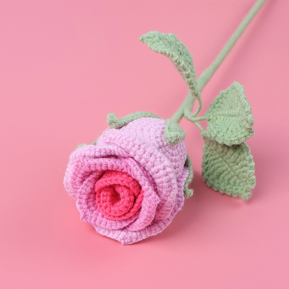 Handmade crochet rose in wine glass on plain background