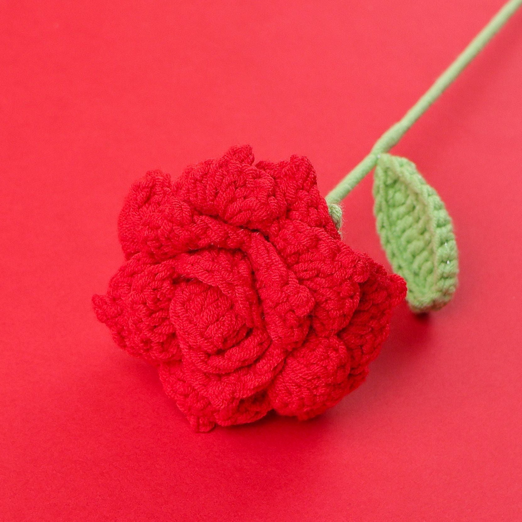 Handmade crochet open rose stem on plain background